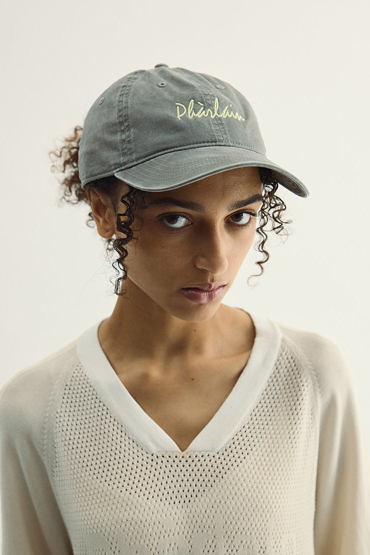 Woman wearing a gray cap with text on a plain background
