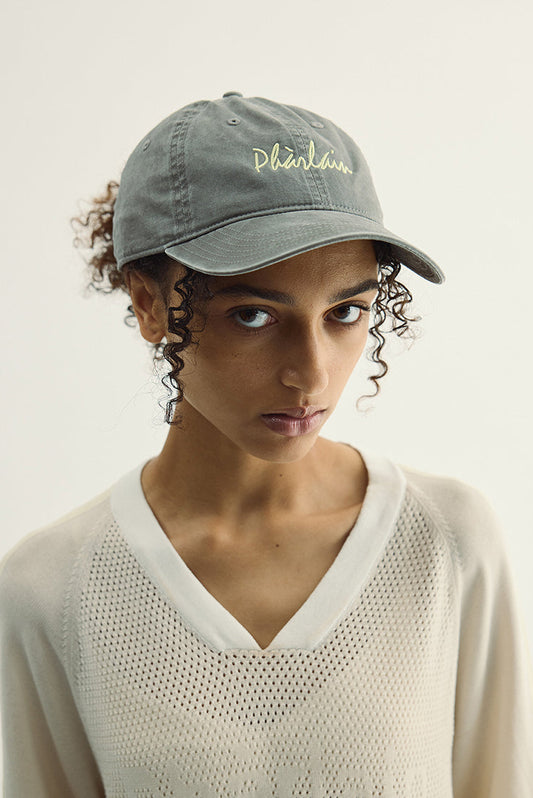 Woman wearing a gray cap with text on a plain background